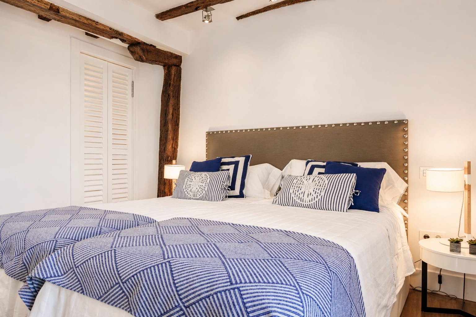 Dormitorio principal con cama doble y textiles en tonos azules en vivienda reformada en Mundaka