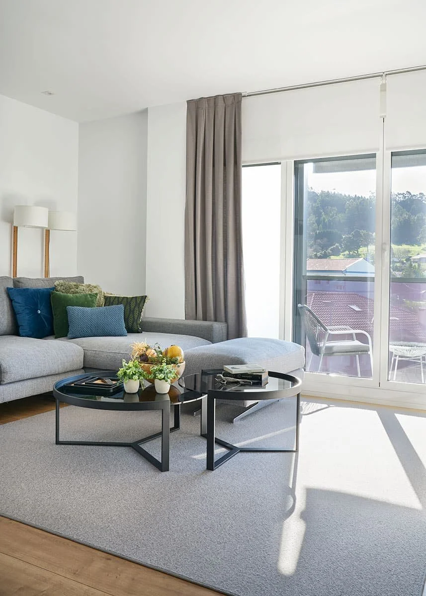 Salón moderno con terraza en vivienda en Urduliz Bizkaia con sofá gris, mesas de centro y luz natural proyecto de interiorismo y estilismo