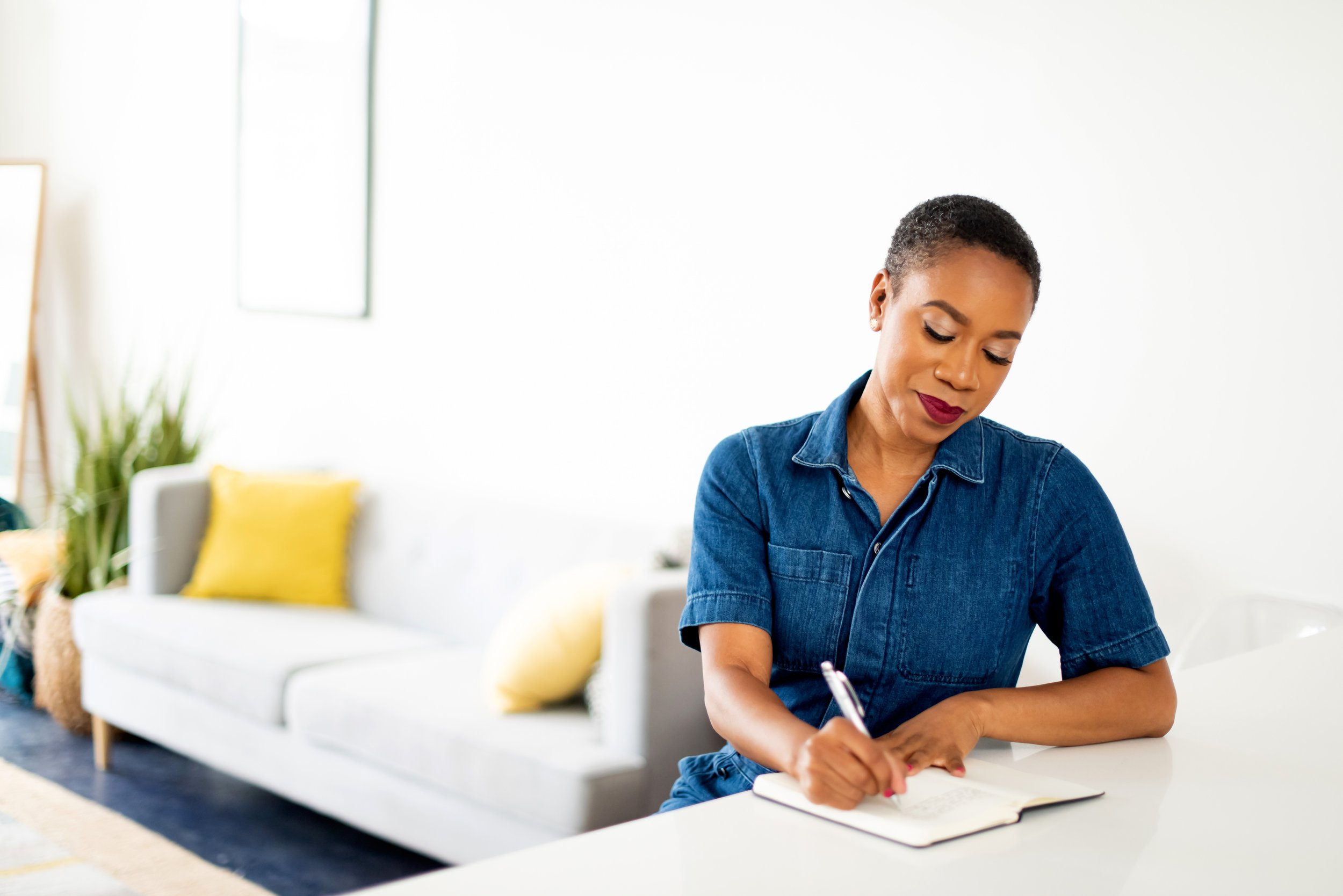 Piper, brown skin, short hair, writing in a journal. Photo Credit: Dfinney