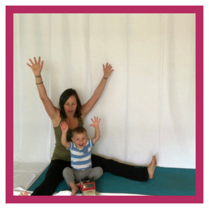 Woman and child on yoga mat with arms in the air.
