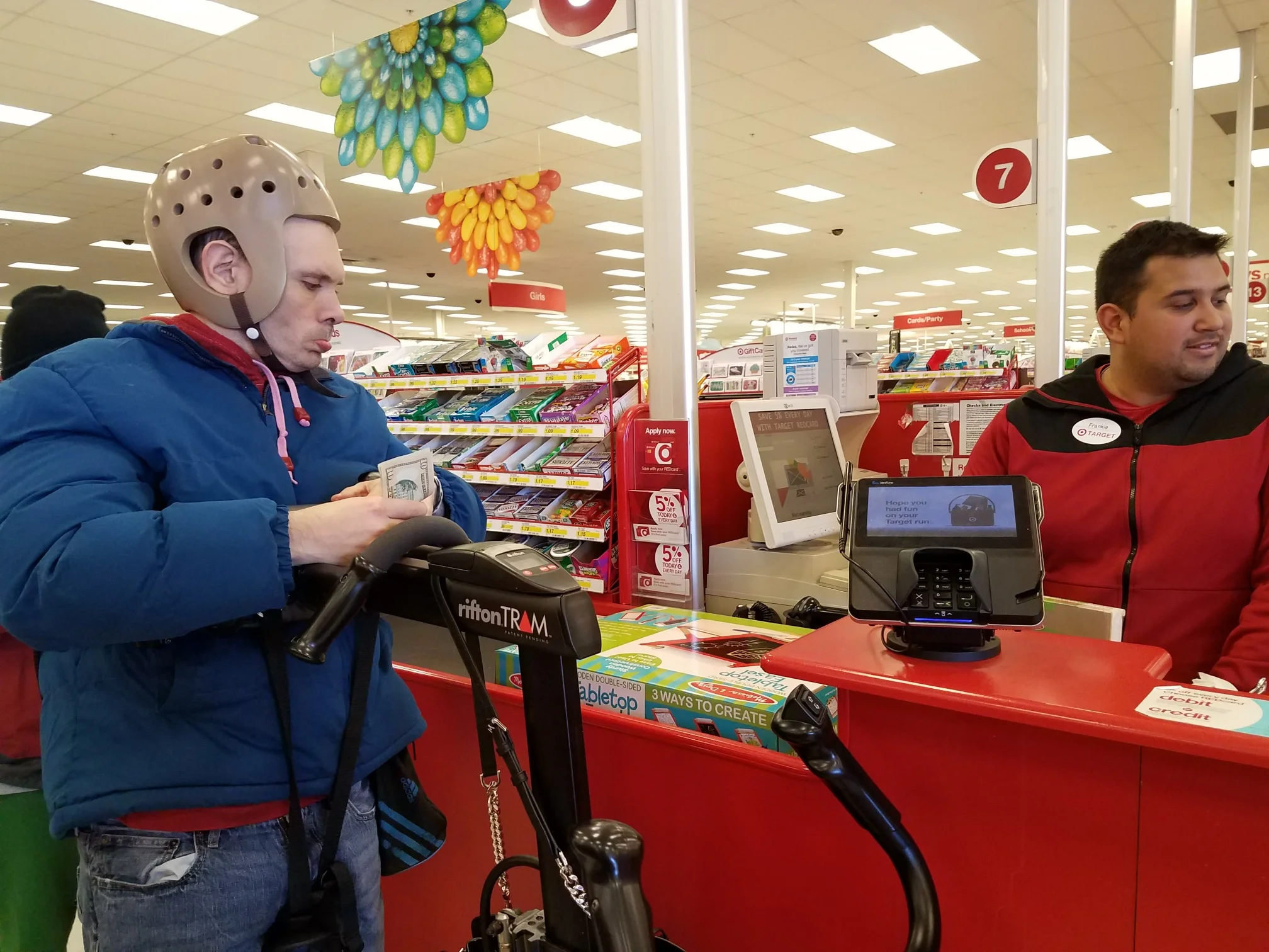 At Chesapeake Care Resources the individuals are out in the community all the time. Some of their favorite activities are going shopping for themselves. Joseph is purchasing an item at the store. Joseph uses the TRAM to allow him independent mobility. He has practiced the skill of using money at the day program before going out into the community.