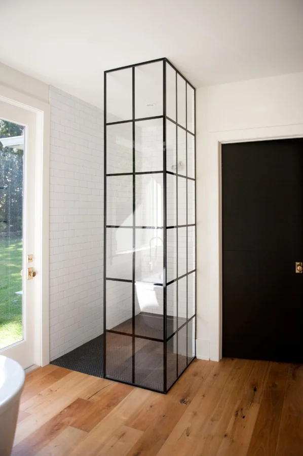  An architectural shower glass enclosure "grid" wraps the black and white shower and provides a focal point upon entering the master bathroom. 