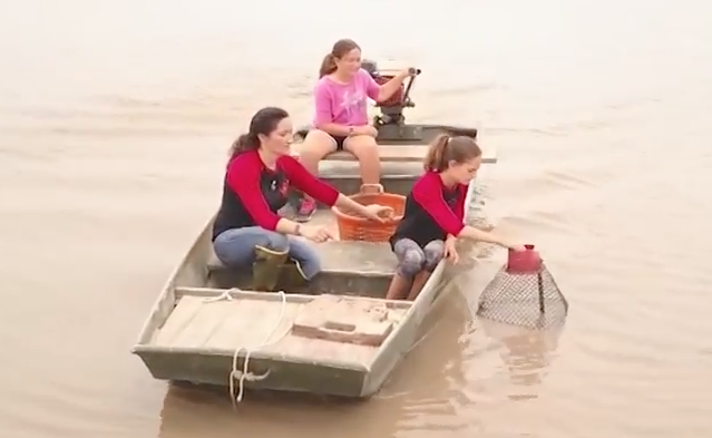 Natachia Stelly baits crawfish traps with two of her daughters on their 2800 acre farm in Vermillion parish.
