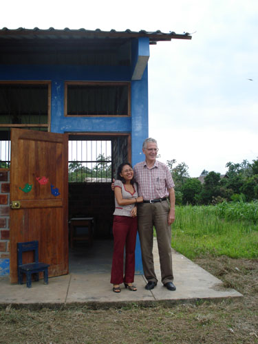 Dean Logan with Besty Dávila Macedo, elementary school teacher, in front of class room building.