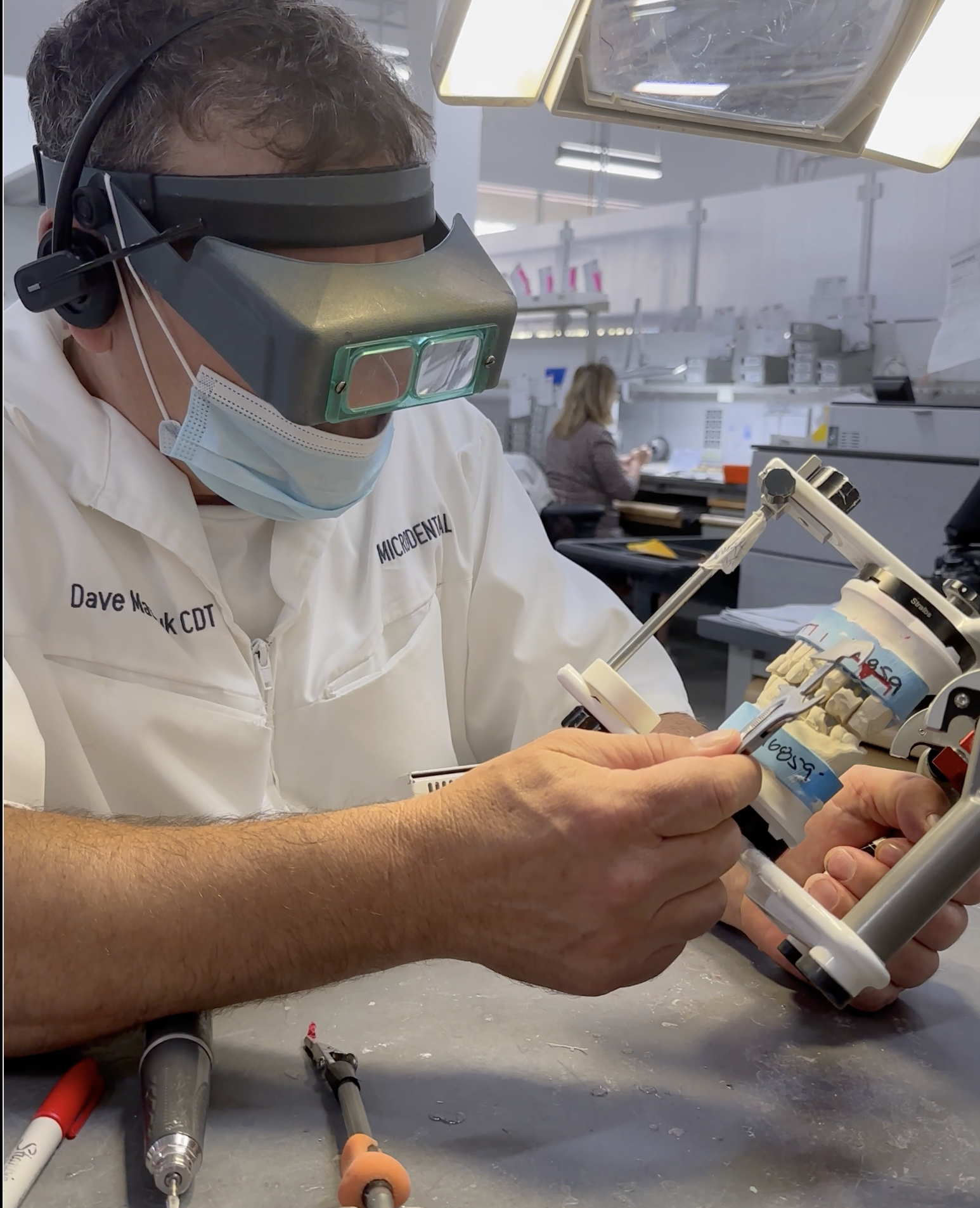 Technician working with a dental model mounted on an articulator.