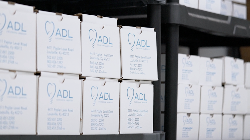 ADL Dental Lab, a MicroDental Lab, shipping boxes stacked on a shelf.