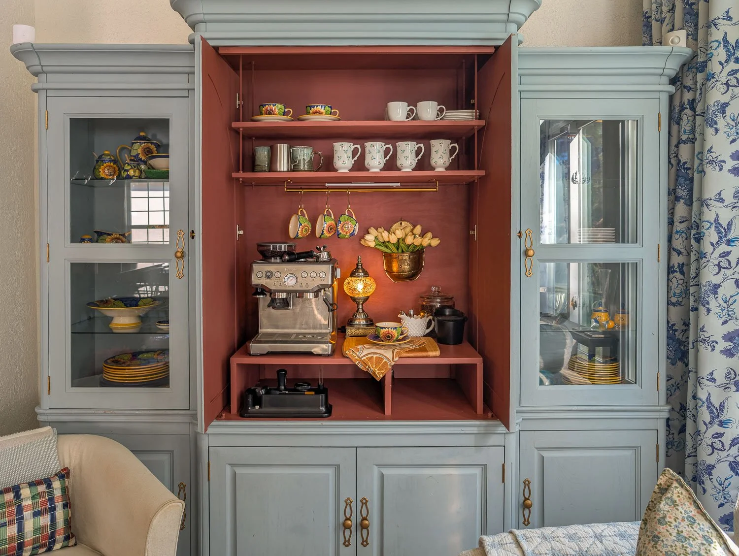 The interior of a media cabinet fully painted in a matte oxblood red, with the surrounding frame painted in a soft heritage blue.