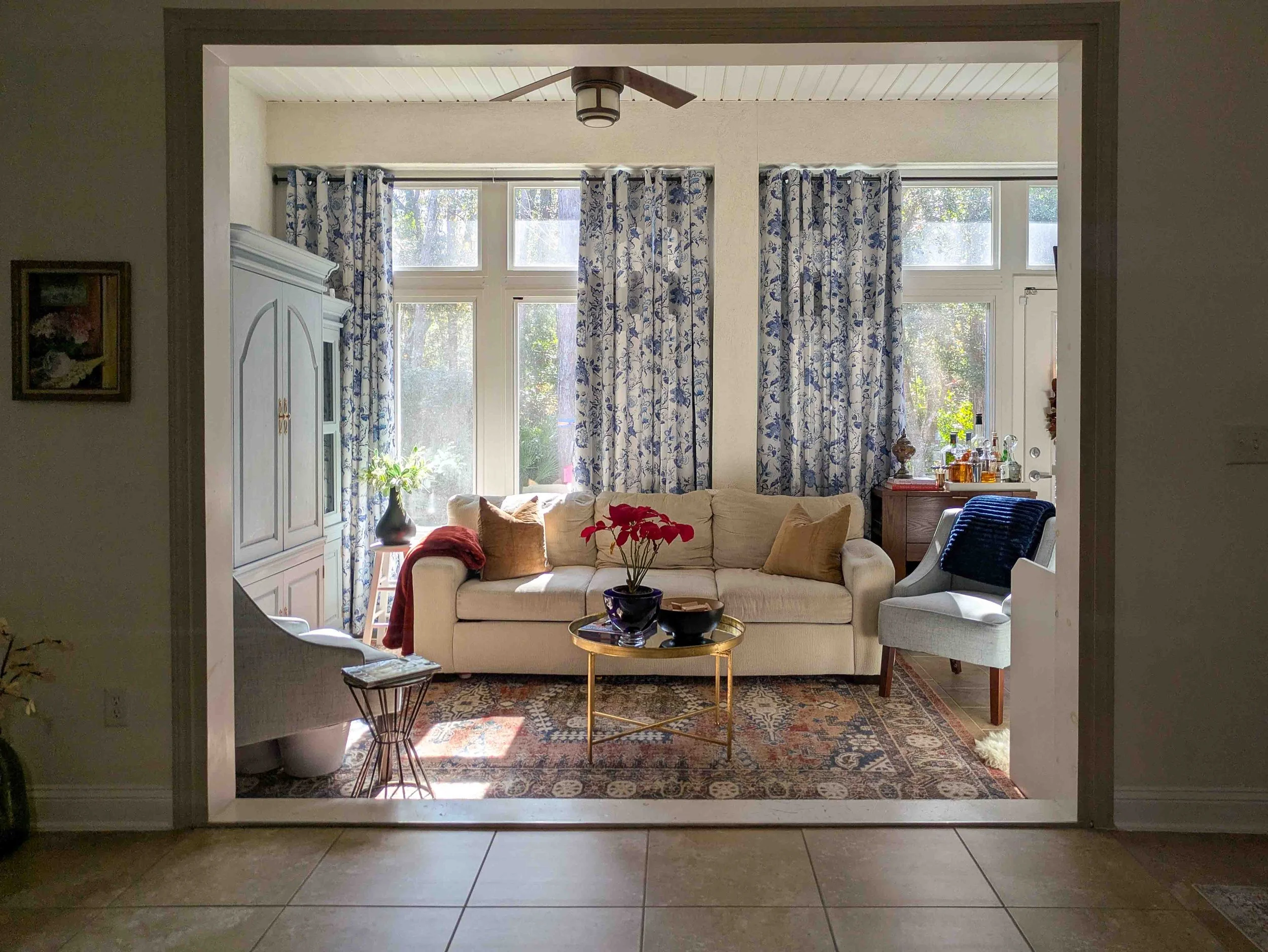 Bright, sunny room with beige couch and blue and red accents.