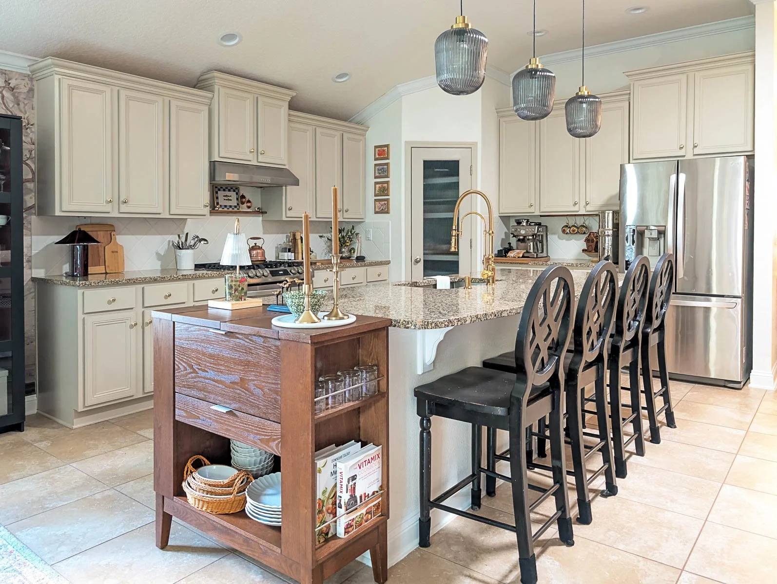A bright and airy kitchen featuring a large granite island with black barstools and gold hardware, showcasing a perfectly clean and organized living space for the 4-Week Refresh challenge.