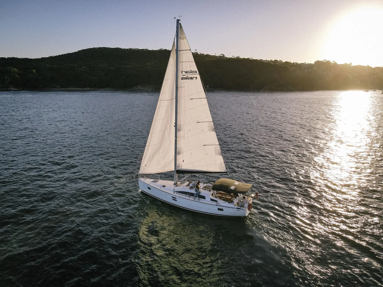 Sailing yacht under full sail on Sydney Harbour at golden hour during a private sailing charter