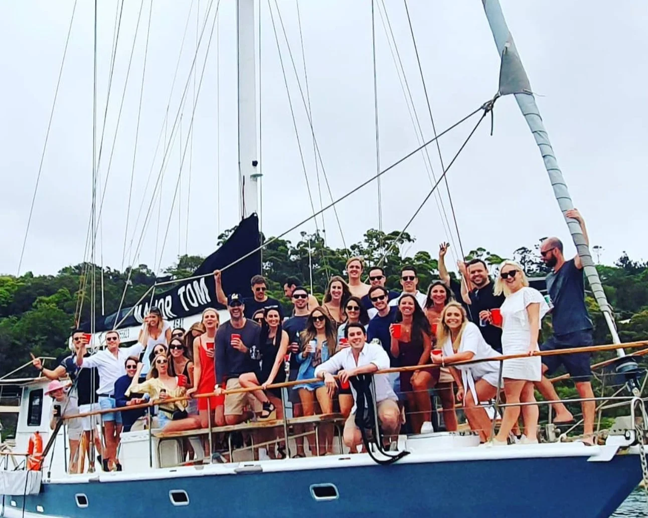 Large milestone birthday group of about twenty five guests celebrating along the rail of a charter yacht on Sydney Harbour