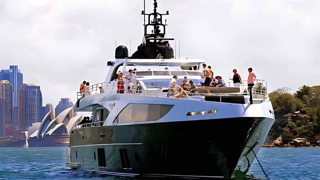 Superyacht on Sydney Harbour with guests on the upper deck and the Sydney Opera House behind
