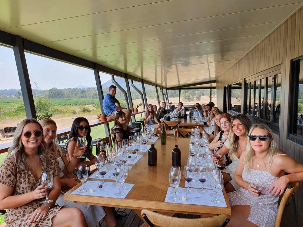 A large group at a long lunch on a sunny verandah with Urban Legends