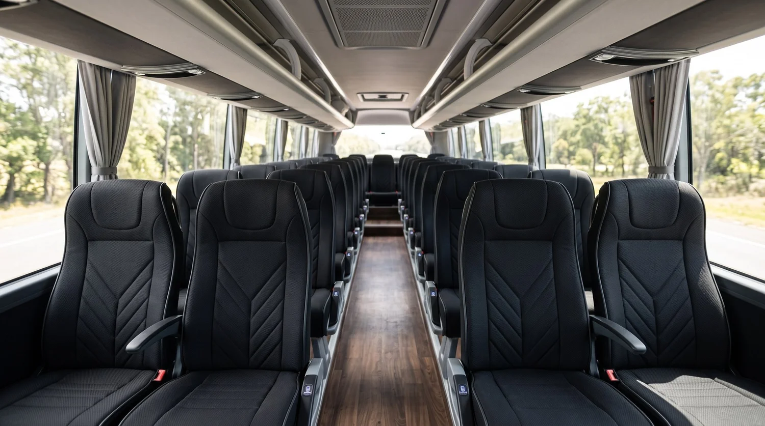 Interior of a 24 seat executive coach with black bucket seats and a woodgrain floor