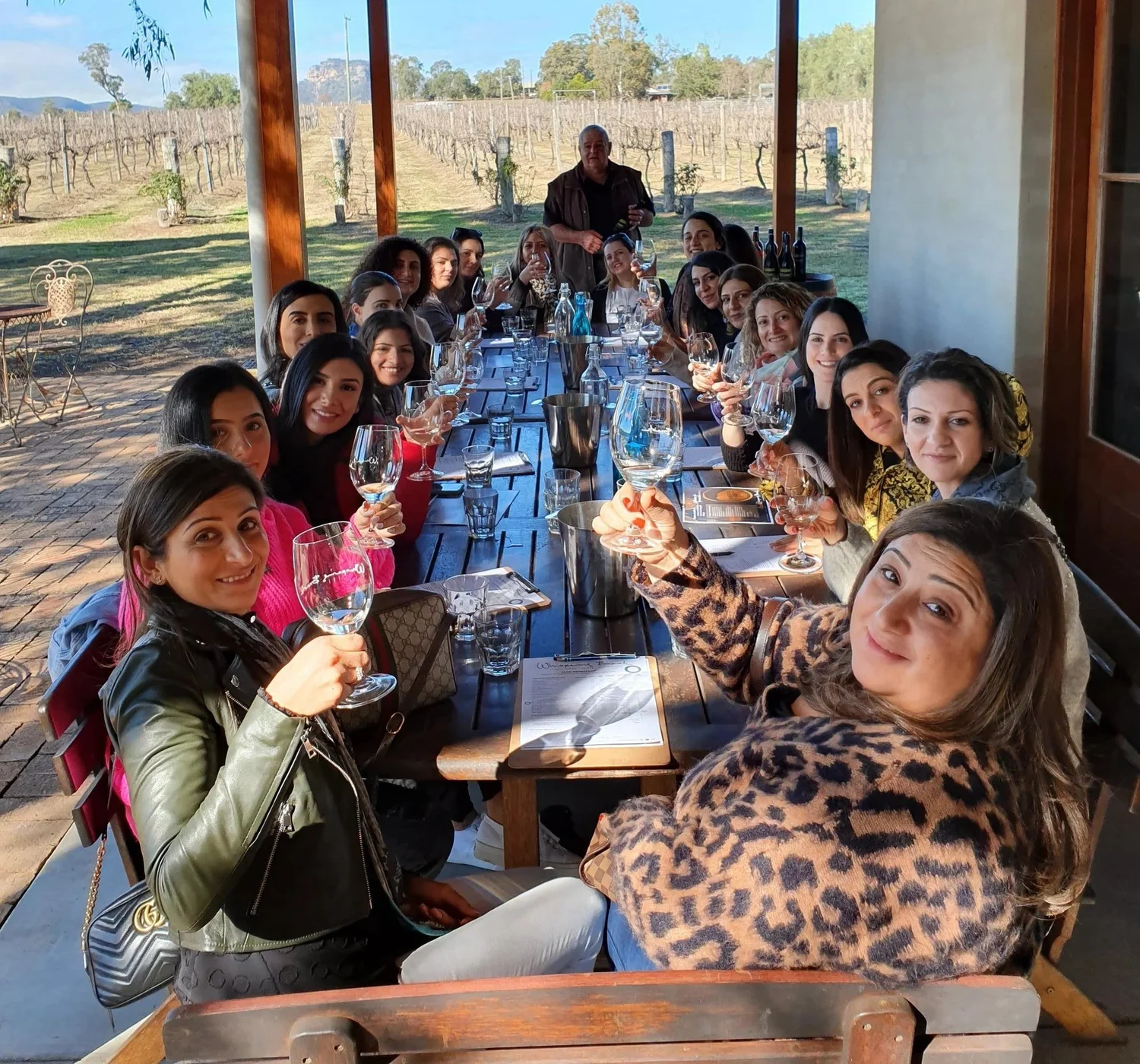 Work group raising a toast around a long lunch table overlooking a vineyard
