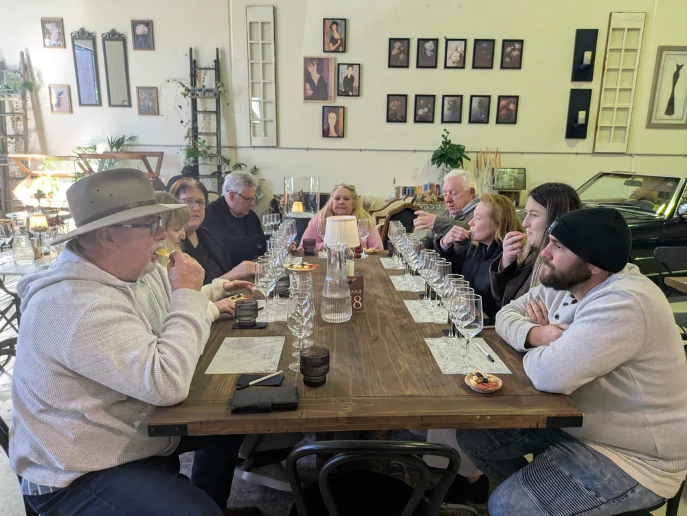 A small private group at a long seated wine tasting in a Southern Highlands cellar door