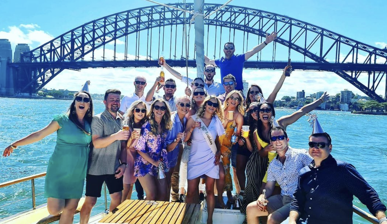 Corporate group toasting on the deck of a Sydney Harbour yacht charter under the Sydney Harbour Bridge