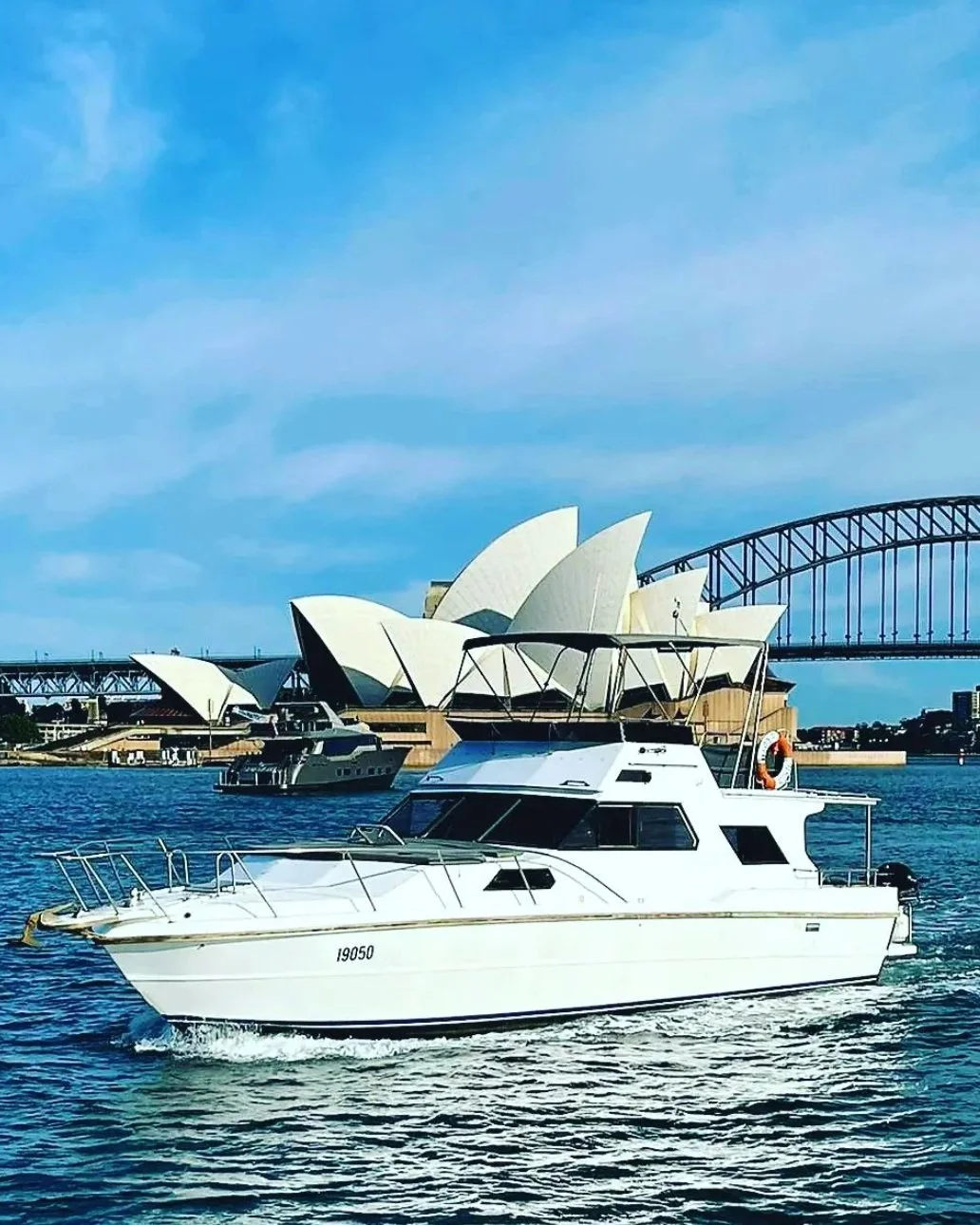 Charter yacht under way on Sydney Harbour past the Opera House and the Harbour Bridge