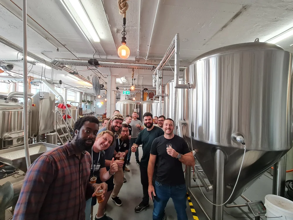 Group of blokes with beers in hand among the tanks on a Brisbane brewery tour