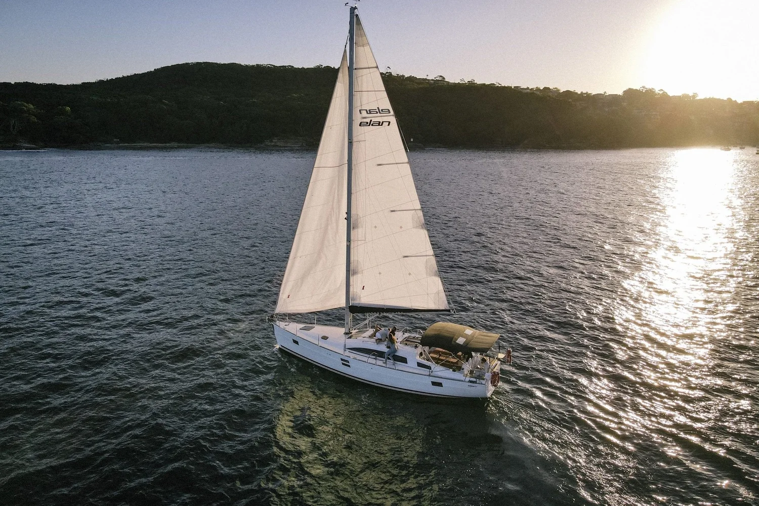 Charter yacht running back across Sydney Harbour in low golden evening light at the end of a charter