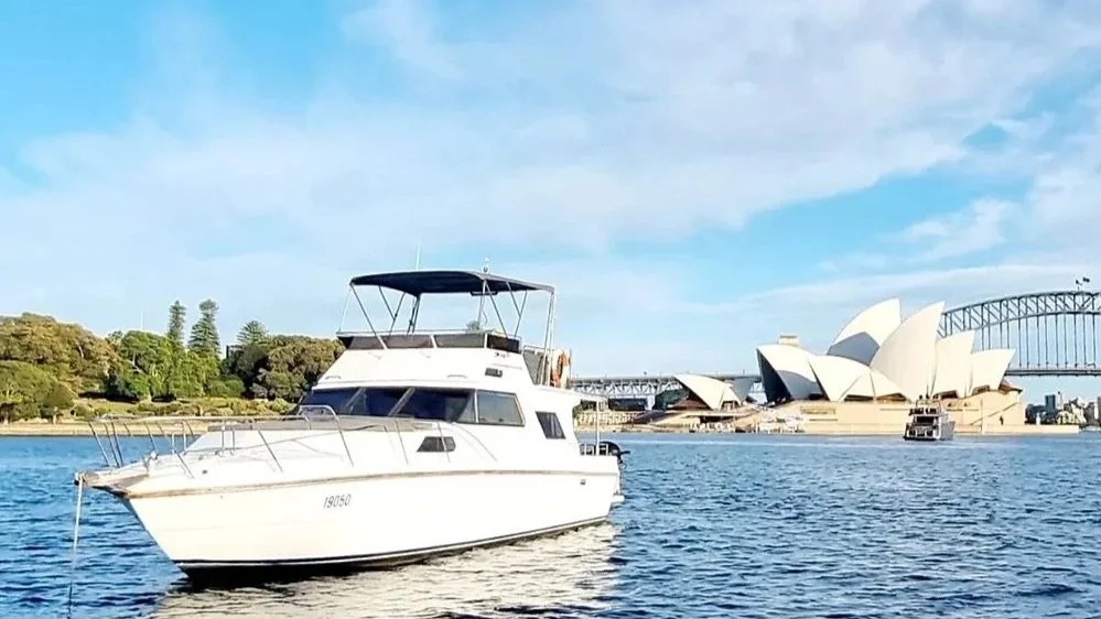 Motor yacht on a Sydney Harbour charter with the Sydney Opera House and Harbour Bridge behind it