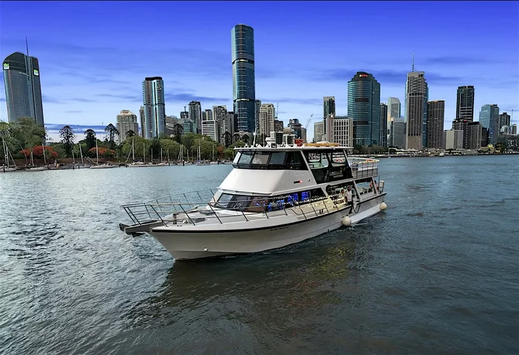 A private motor yacht on the Brisbane River with the city skyline behind