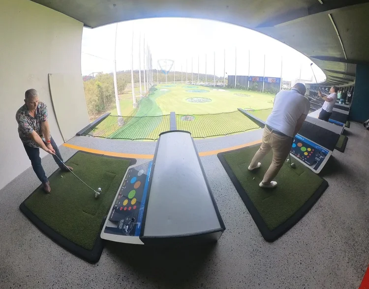 Two players hitting balls from a Topgolf bay