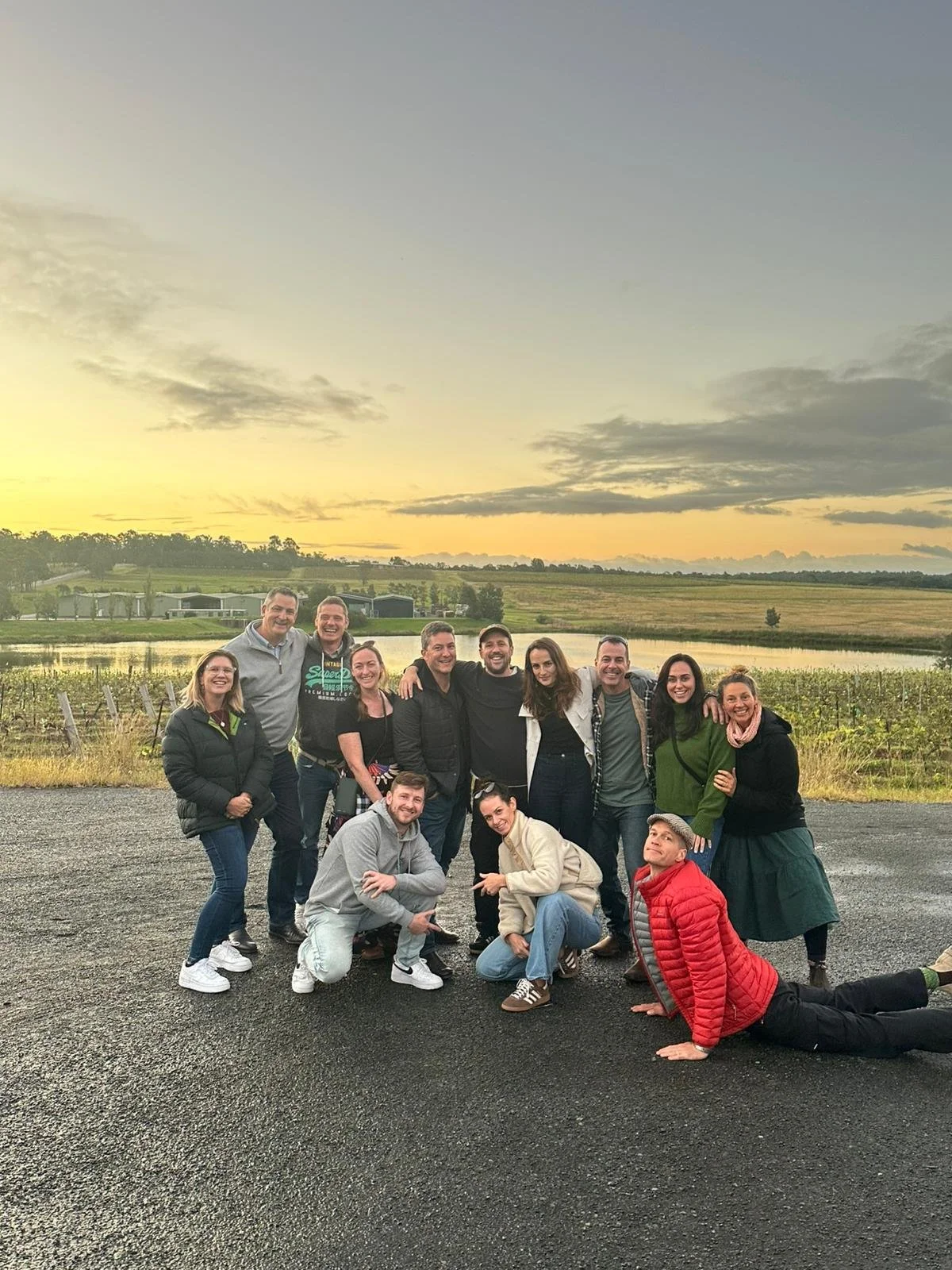 A team of colleagues smiling together on a country road at sunset during a work celebration