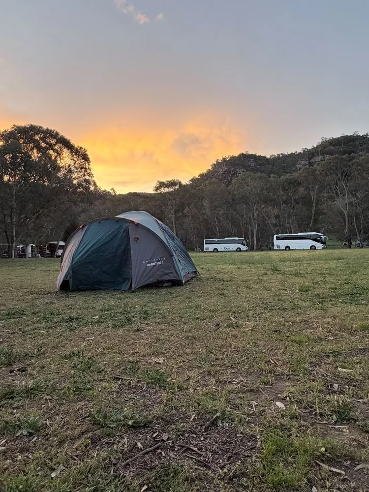Urban Legends coaches parked beside an expedition camp at sunset