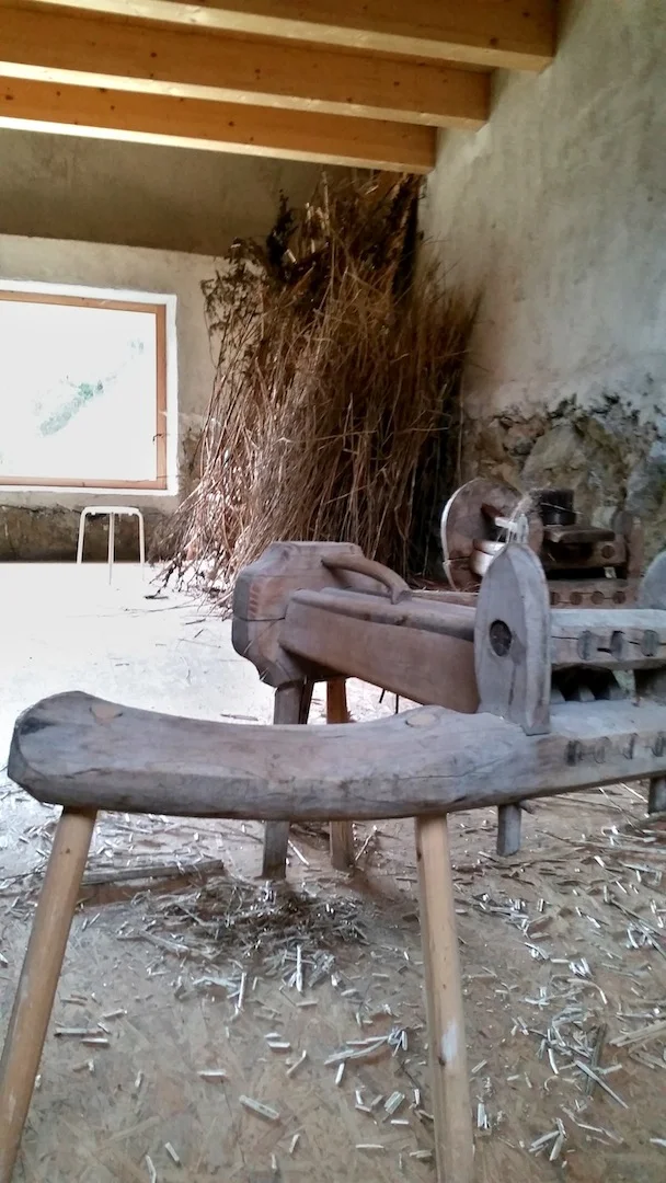 In the corner: Dried hemp stalks. Each stalk must be pressed using the wooden mechanism (pictured in the foreground) to separate the shell from the fiber. Once the shell is discarded, the fibers are combed and can be spun into yarn.