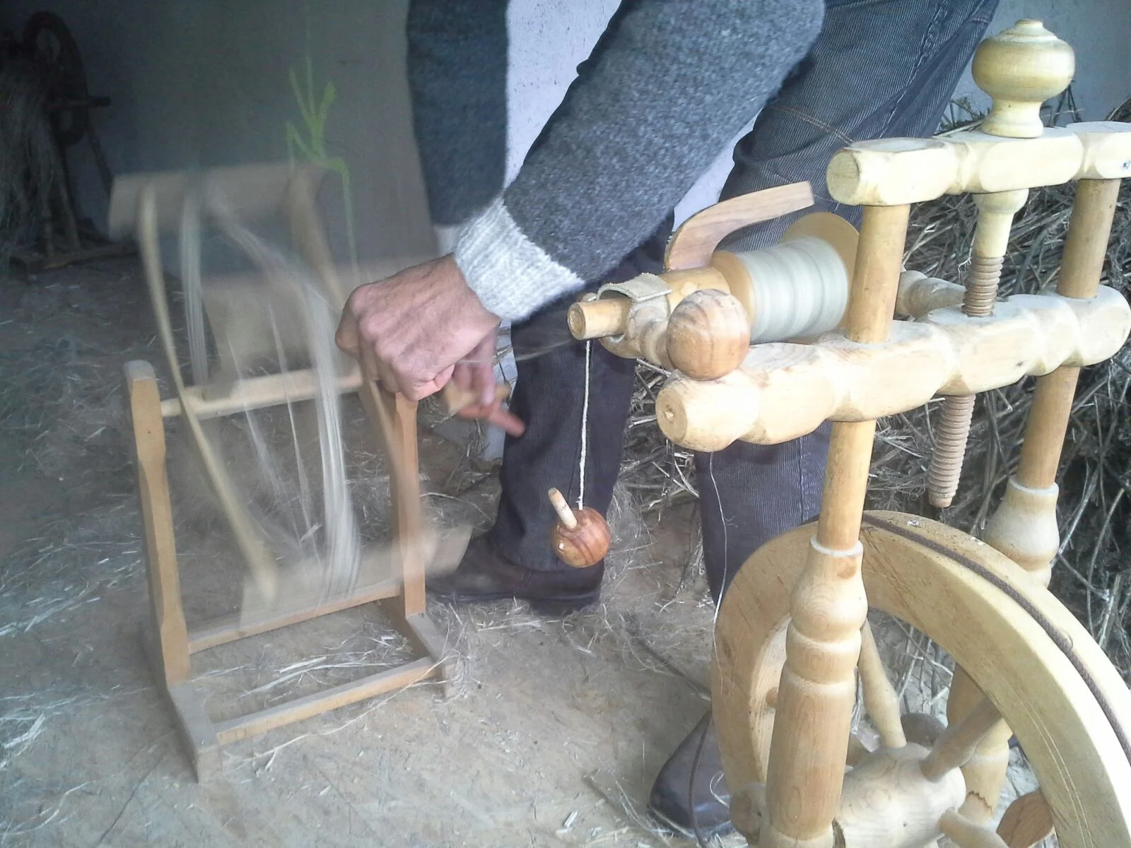 Using a skein winder to empty the bobbin of the finished yarn.