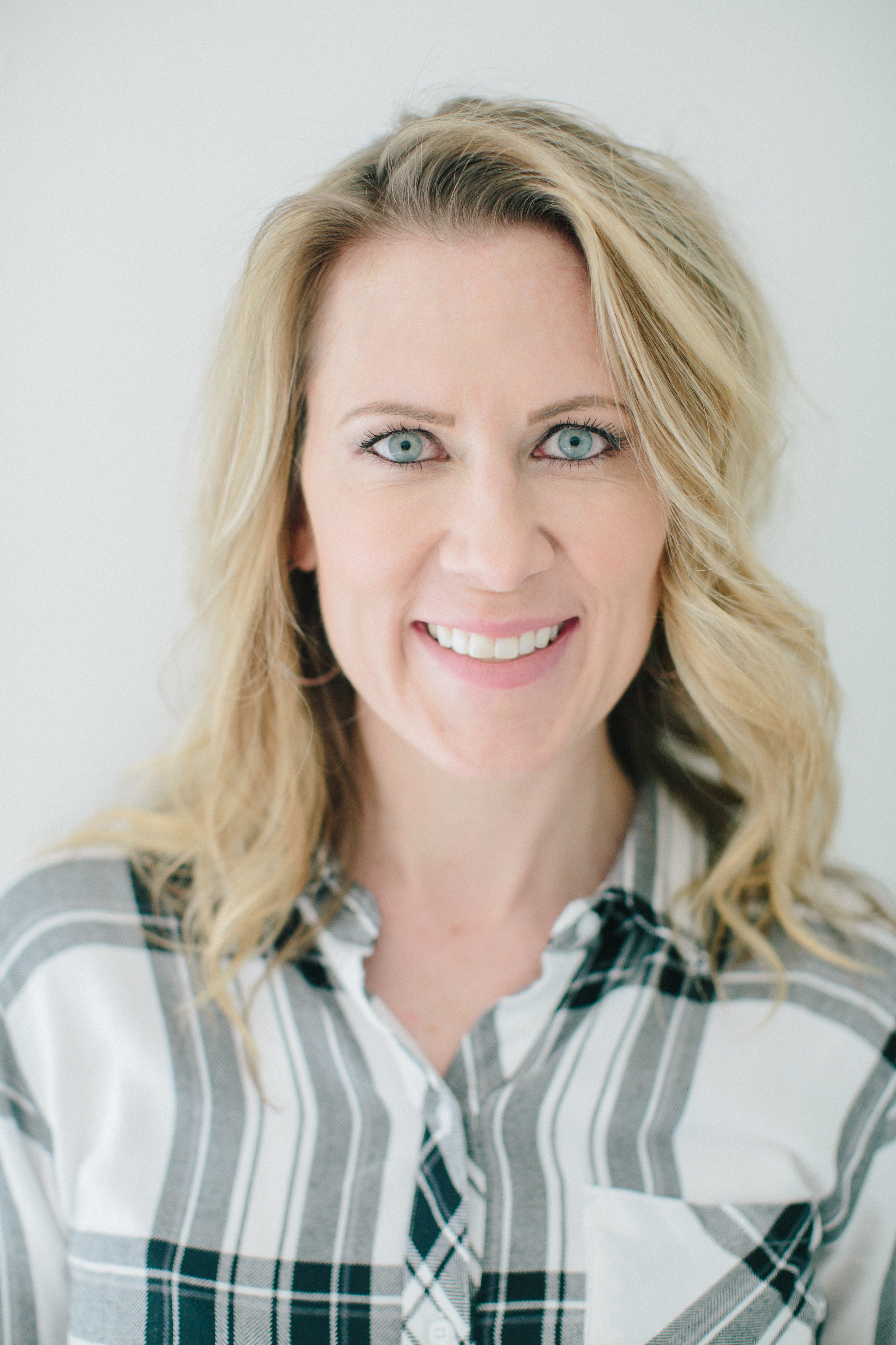 Dr. Nicole Forsgren, a DORA metrics expert and devops consultant wearing a plad shirt and smiling.