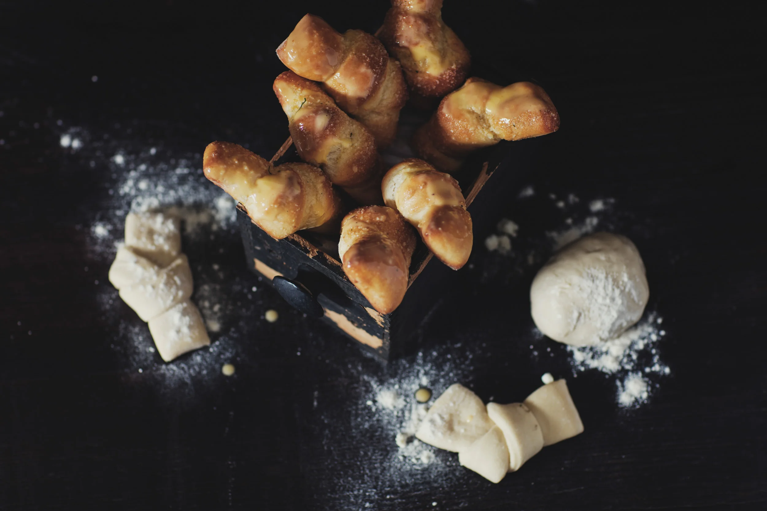 Fresh baked garlic twists with raw garlic twists on table