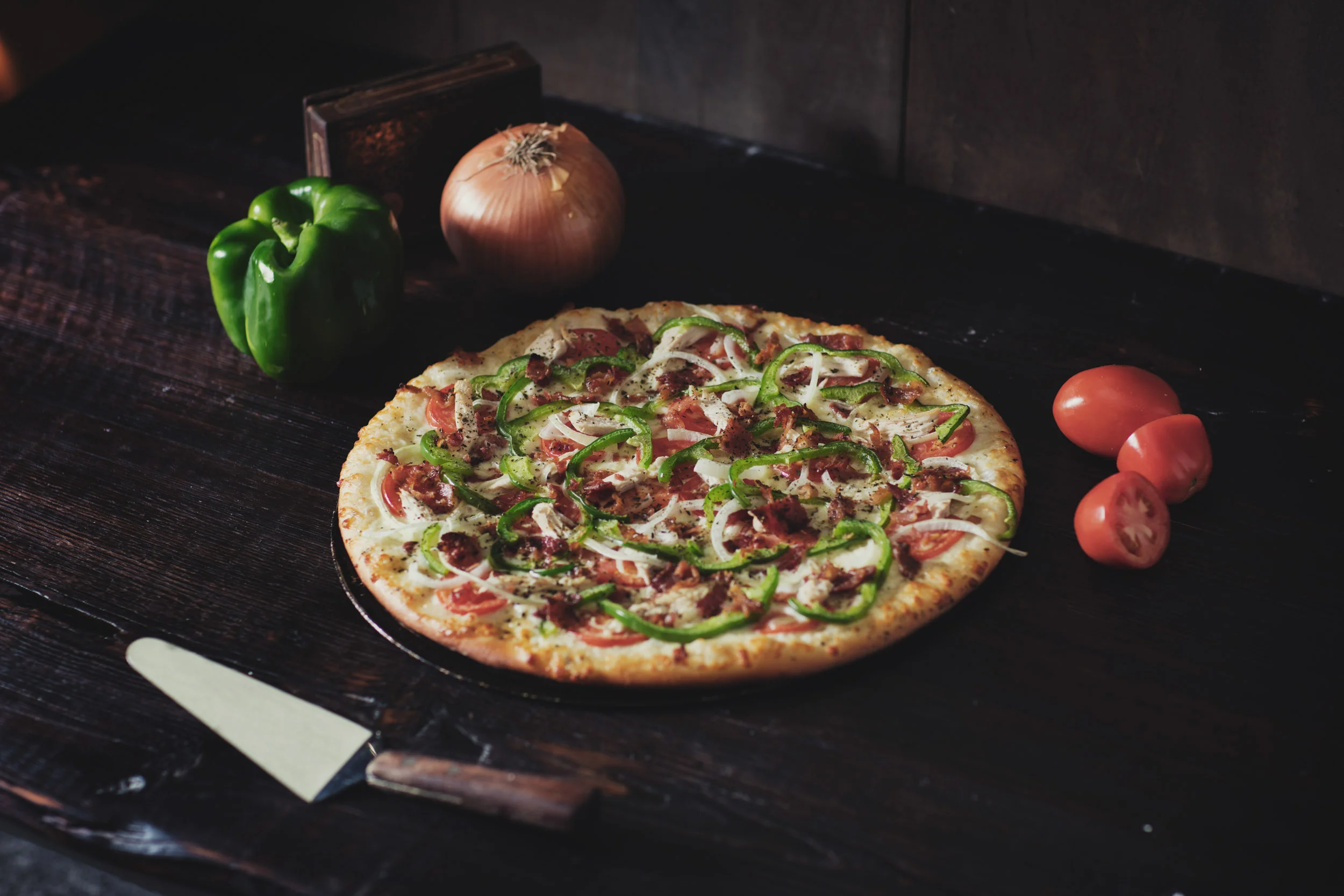 Fresh baked hand tossed pizza with tomato, green pepper, and onion on table