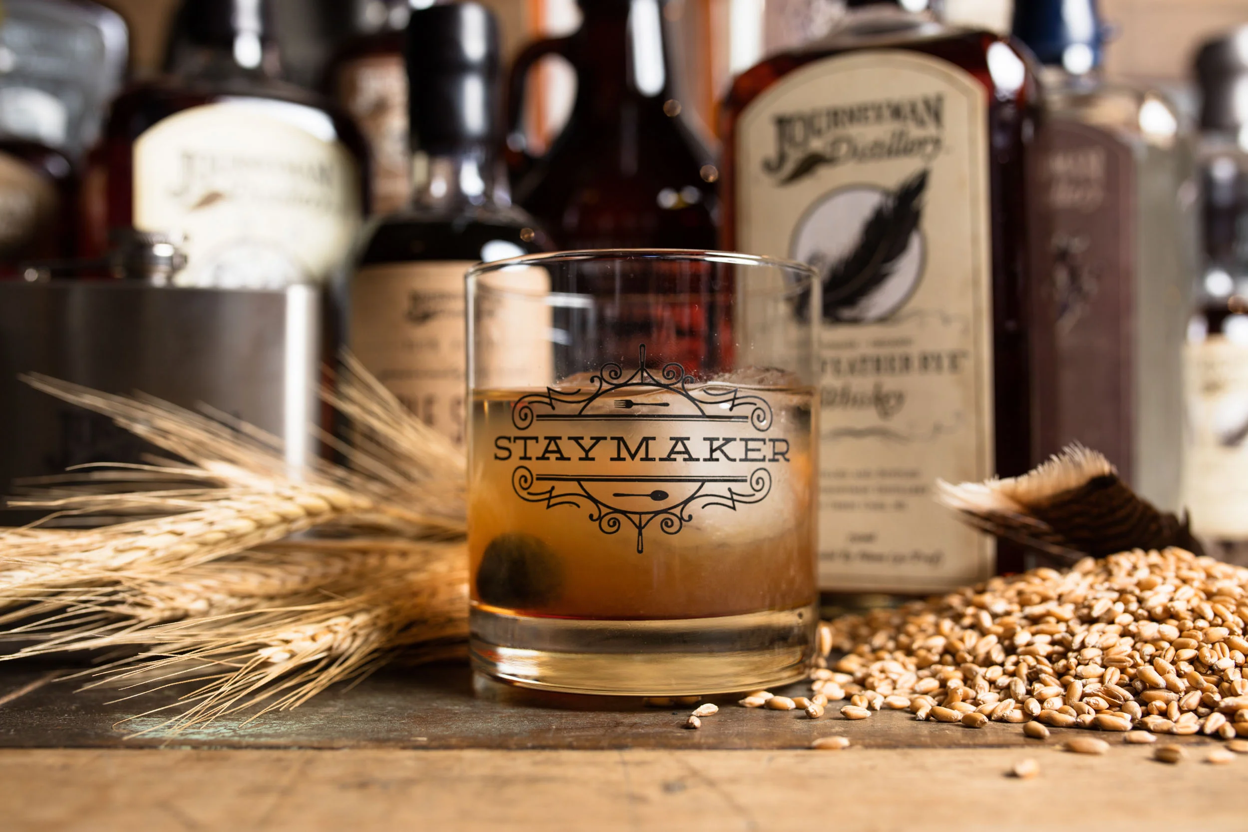 Journeyman Distillery whiskey in a rocks glass with grain on a wood table