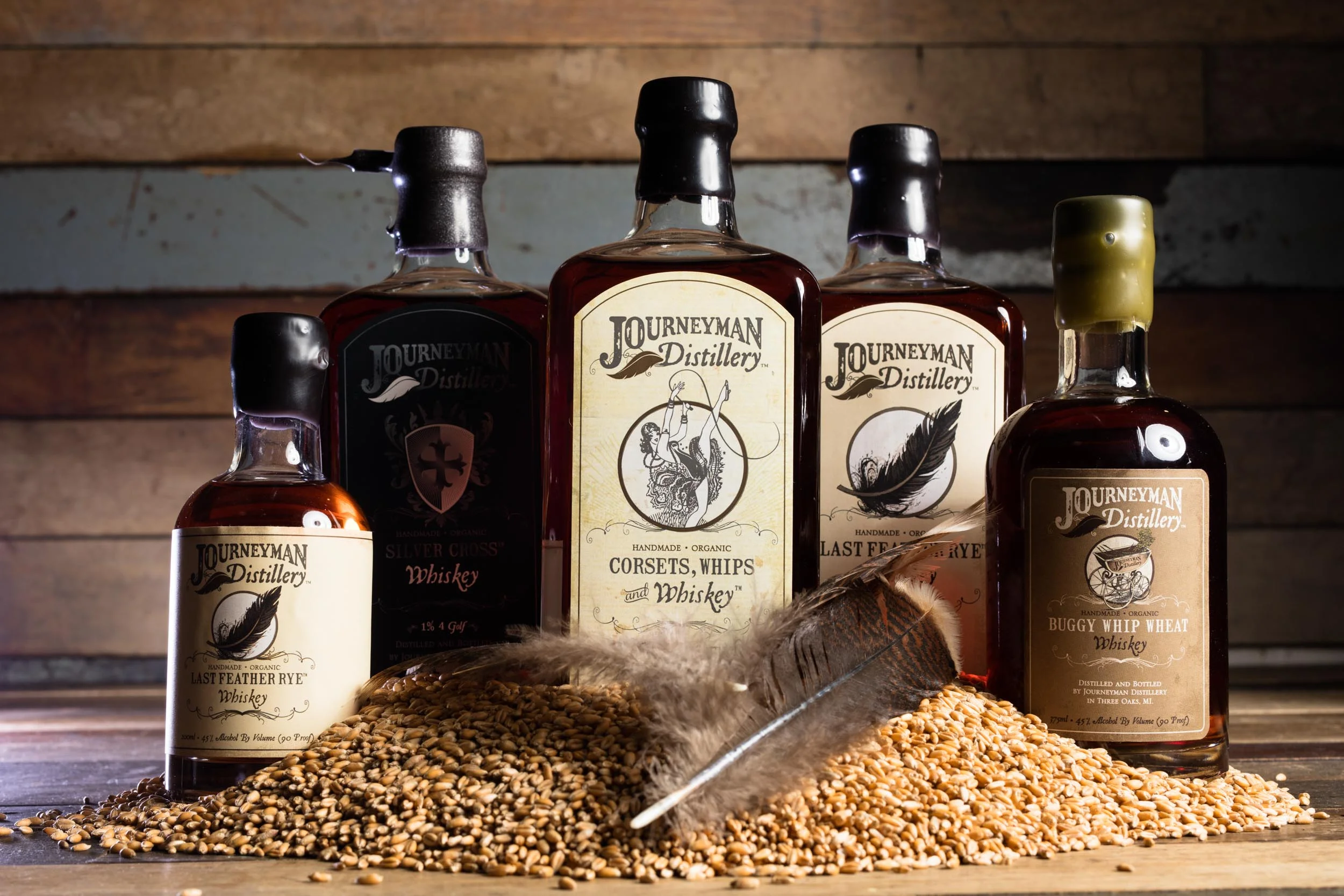 Journeyman Distillery whiskey with grain on a wood table