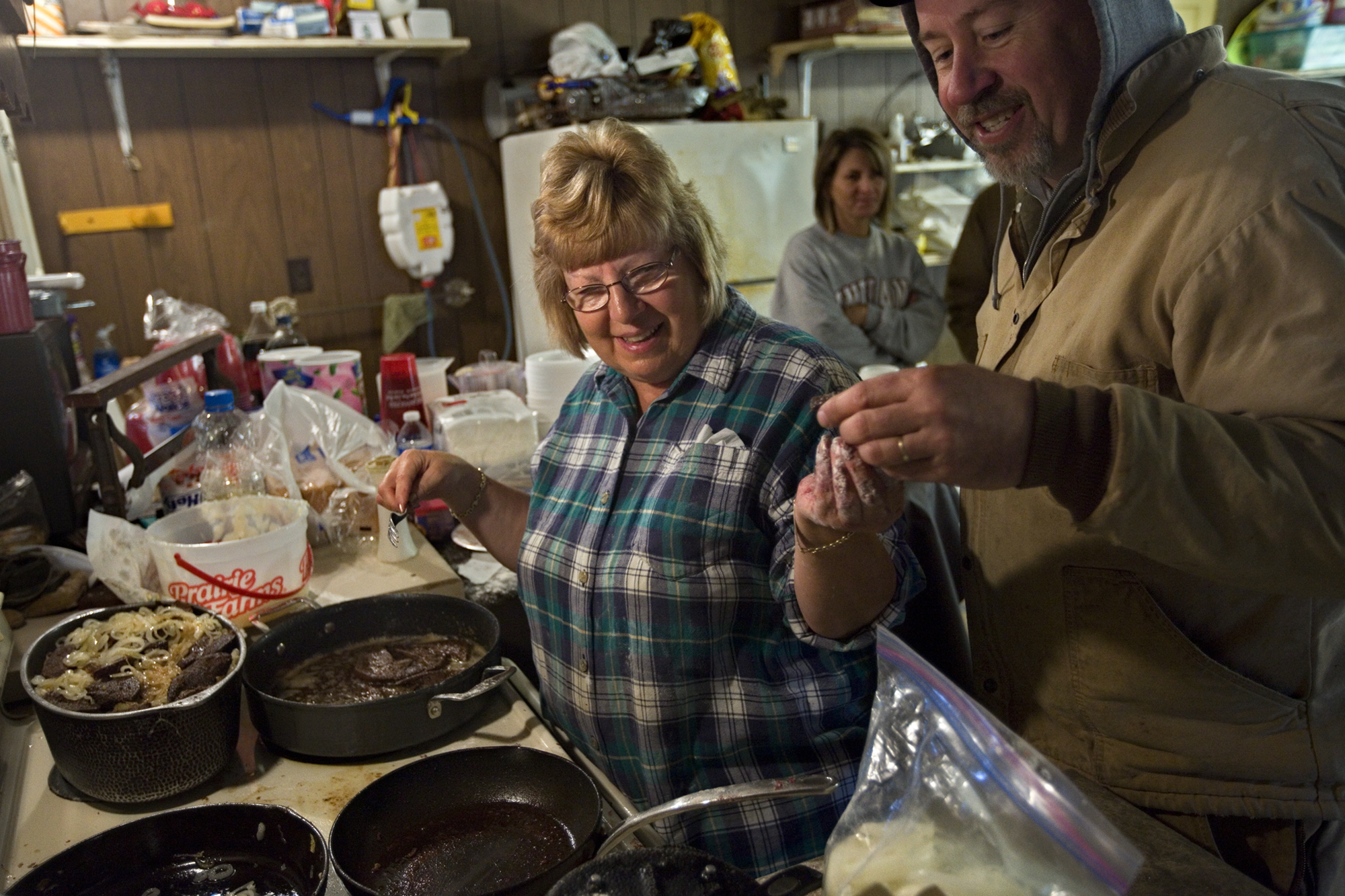 Marilyn “Toot” Schwenk of Ireland handed her brother-in-law Roy Main of Ireland a freshly cooked piece of liver as she made liver and onions for the family to eat for lunch on the second day of butchering.