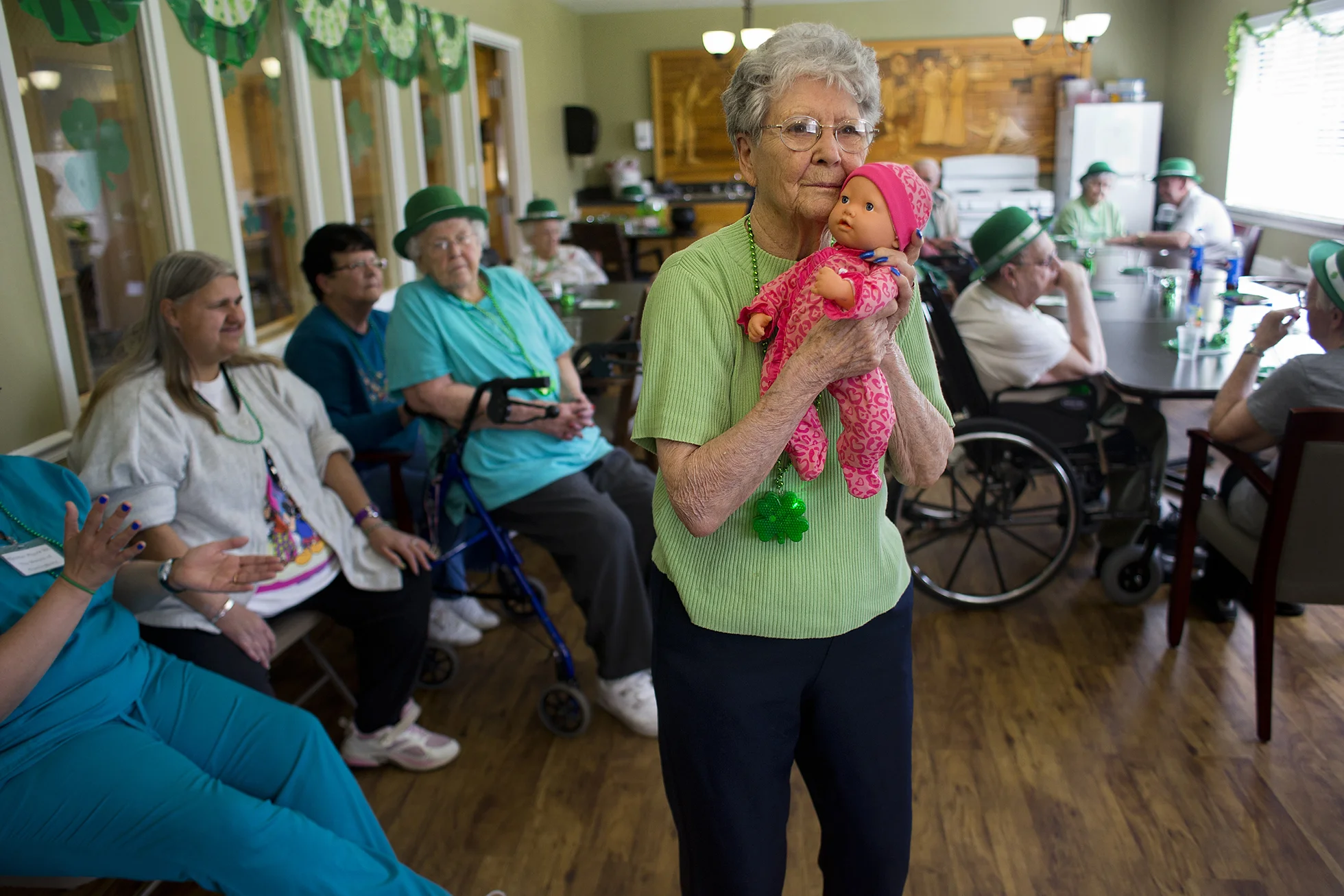 Cuddling with her baby doll, The Waters of Huntingburg resident Marge Short swayed side-to-side to the music during a St. Patrick's Day celebration for residents in the Hope Springs wing of the Huntingburg facility. Hope Springs is a unit with specialized care for residents with Alzheimer's and dementia. Short, who has dementia, has three dolls she enjoys caring for on a daily basis. Two of the dolls are her granddaughter's former dolls from more than 20 years ago.