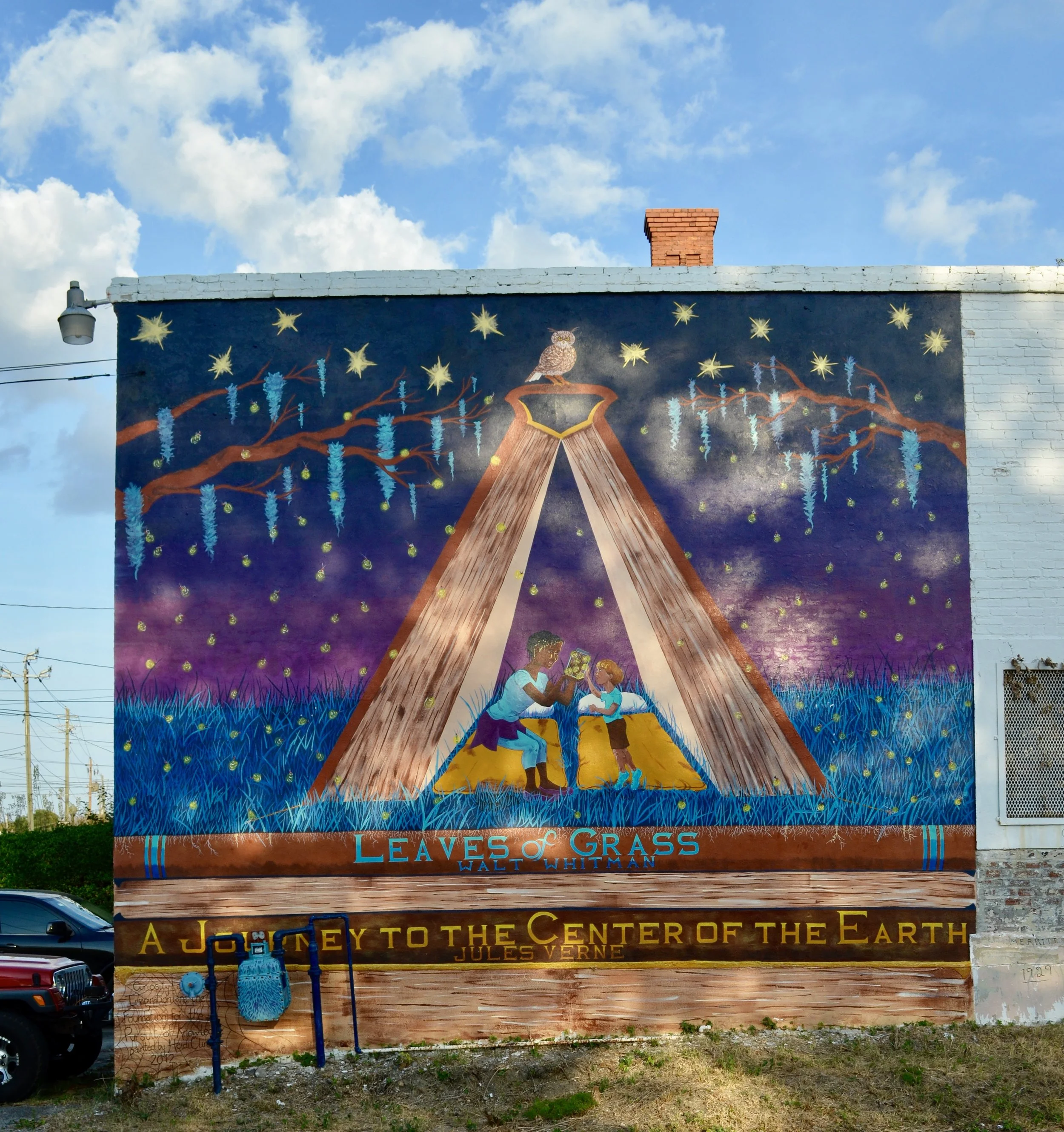 Actual mural on College St. Title: Curiosity and Imagination are the Foundation for the Pursuit of Knowledge. Two kids out camping admire the magic of fireflies in a jar. Their tent is an open book. The ground they stand on, the layers of earth, is actually a stack of books that have been known to inspire people for over a century. Painted with a grant from College Hill Alliance and the Facade Squad in 2012.