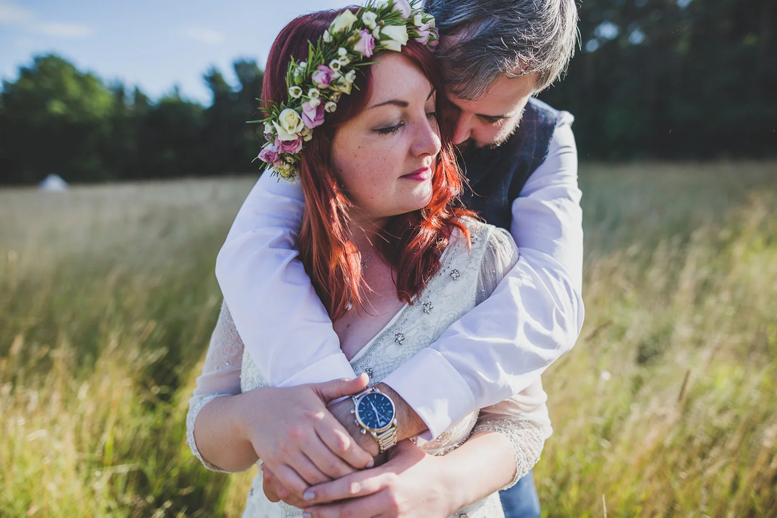 a bride and groom hug closely in a field. camp katur wedding north yorkshire tipi wedding venue glamping. stop motion wedding films uk