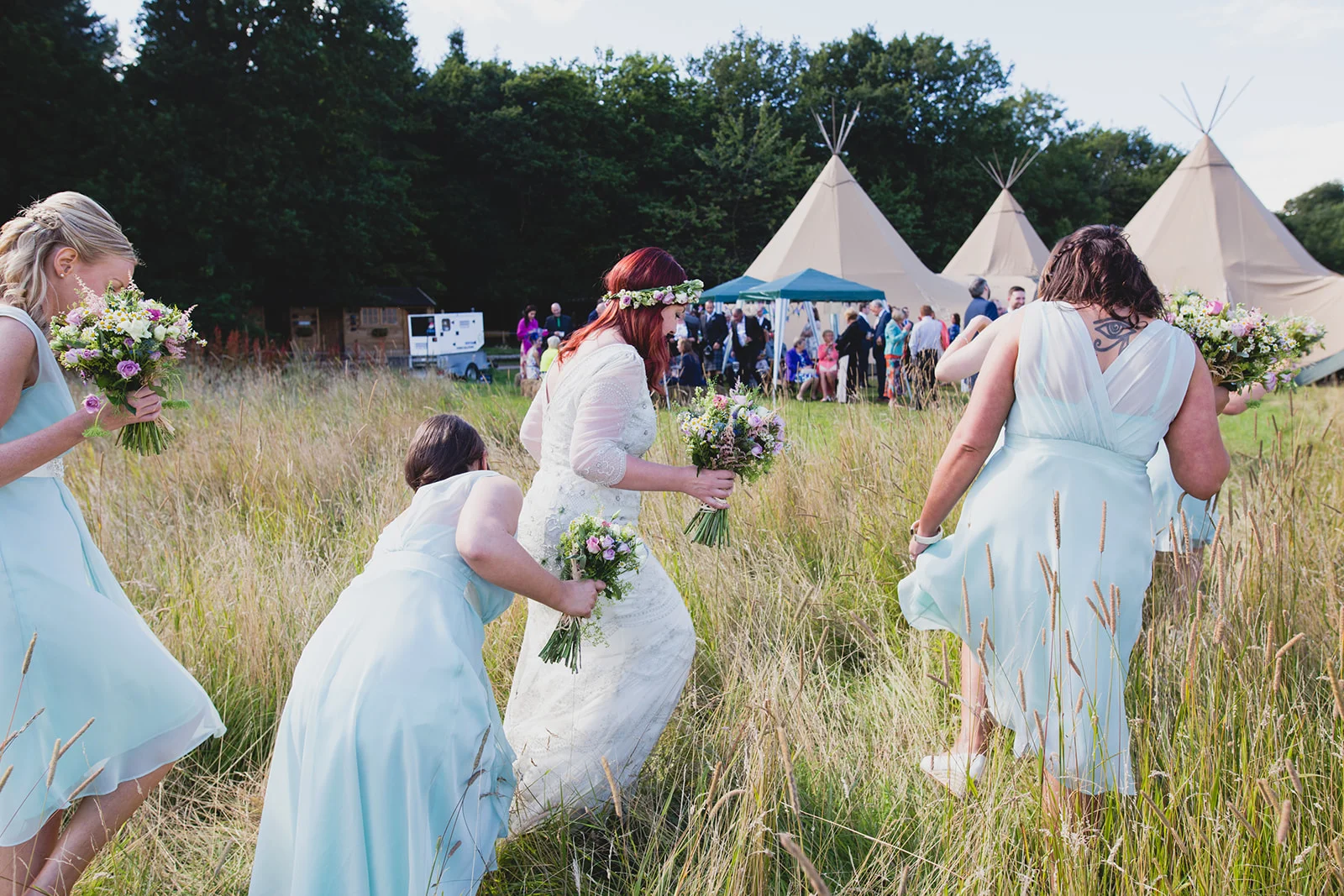 a bride and her bridesmaids walk through the field towards a tipi. camp katur wedding north yorkshire tipi wedding venue glamping. stop motion wedding films uk
