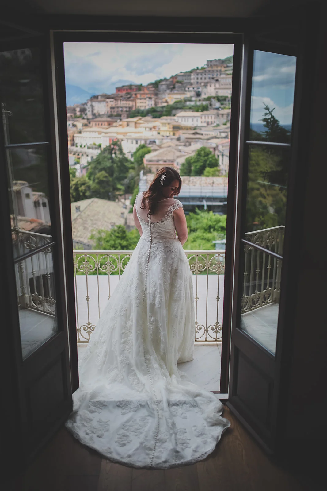 a bride stands with her back to the camera with views of the italian hills in the background. destination creative wedding photography italy. stop motion wedding films uk
