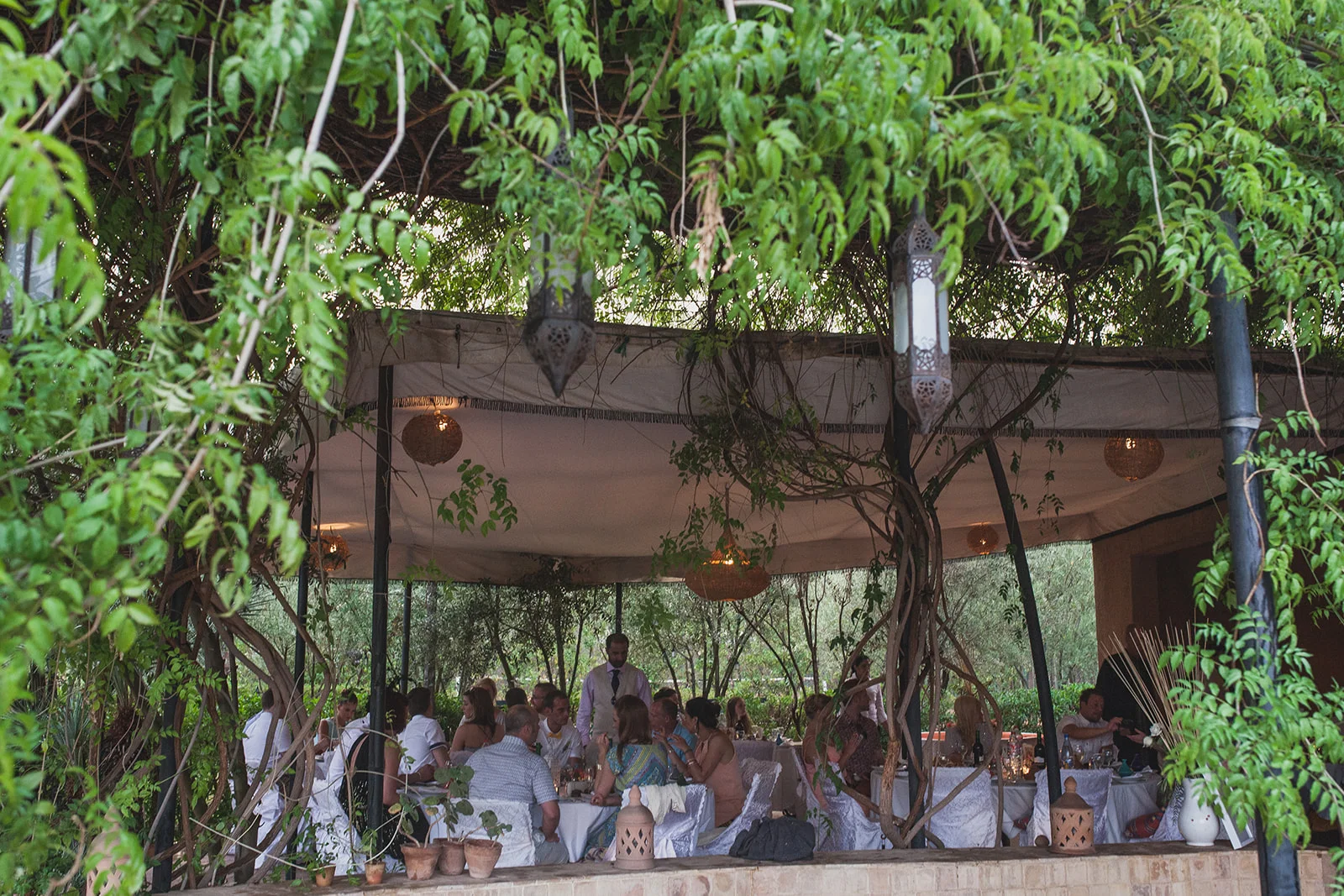 a wide shot of the guests sitting in a botanical looking marquee. fawakay villas marrakech wedding morrocco wedding photography. stop motion wedding films uk