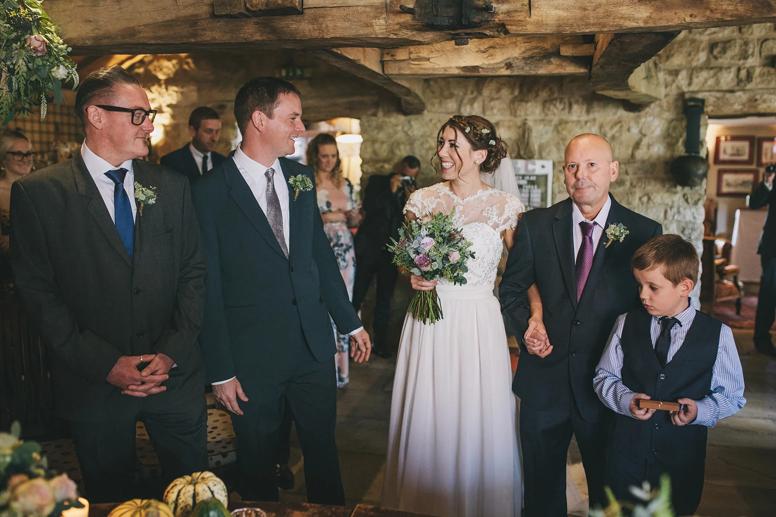 a bride and groom smile at each other at the bottom of the aisle during the ceremony. star inn at harome near helmsley, north yorkshire wedding photographer. stop motion wedding films uk.
