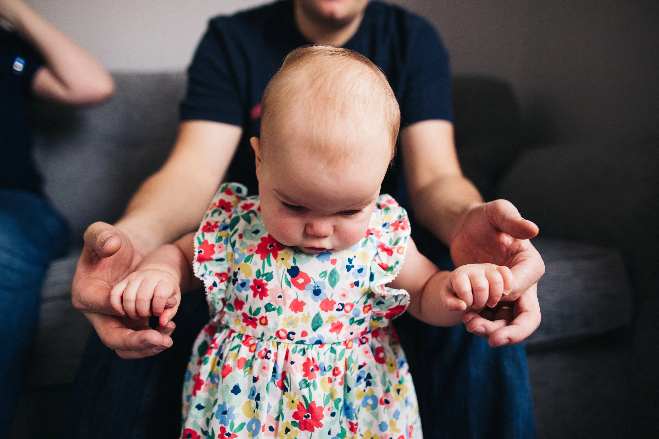 a dad holds his baby girl's hands as she tries to stand up. creative relaxed family photography teesside middlesbrough stockton north east