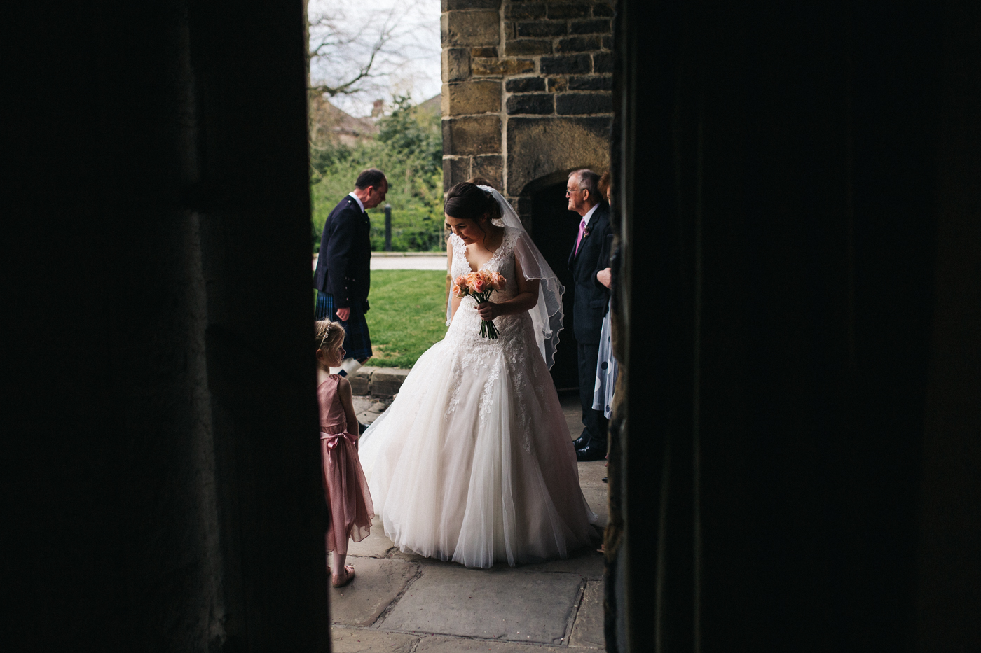 the bride stands outside before entering the ceremony. spring barn wedding at east riddlesden hall keighley west yorkshire wedding photographer