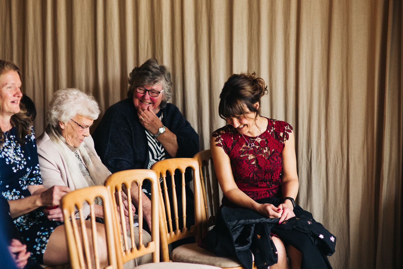 the brides mum laughs in her seat at the ceremony. spring barn wedding at east riddlesden hall keighley west yorkshire wedding photographer