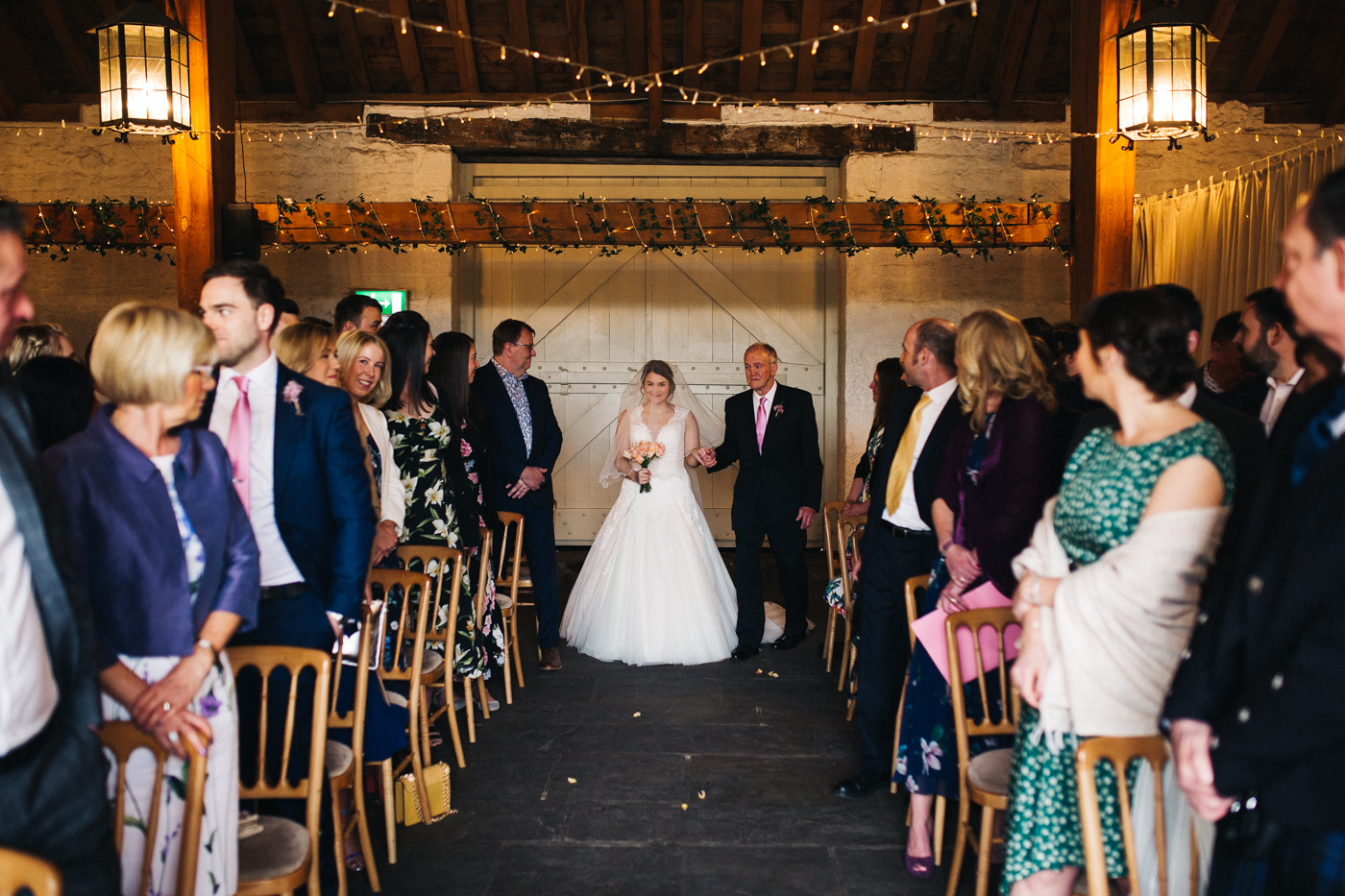 the bride walks down the aisle with her grandad. spring barn wedding at east riddlesden hall keighley west yorkshire wedding photographer