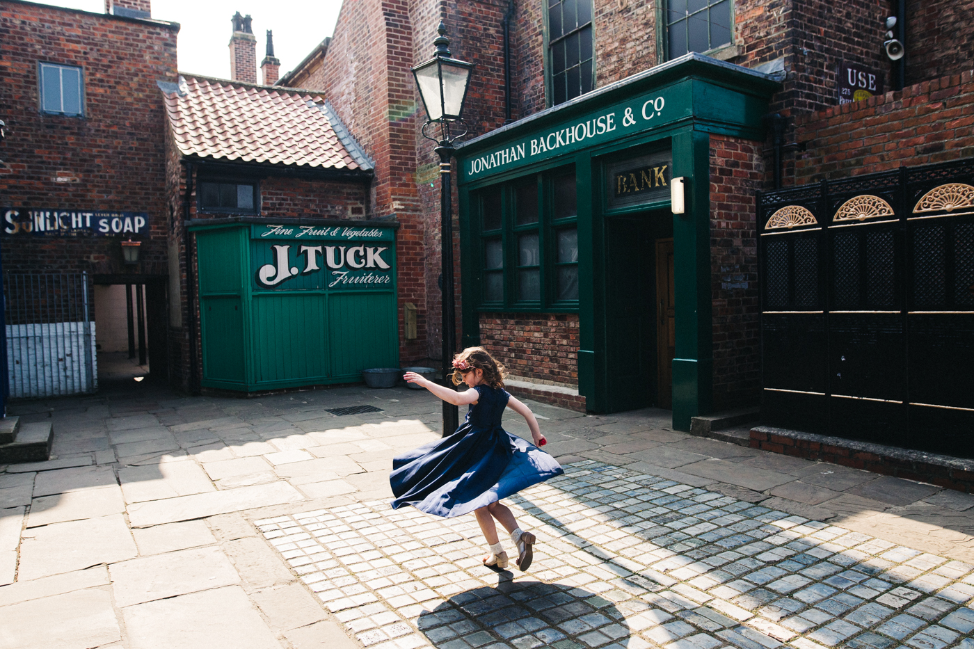 a girl twirls in a victorian street wearing a navy dress. preston park museum wedding stockton teesside middlesbrough wedding photographer
