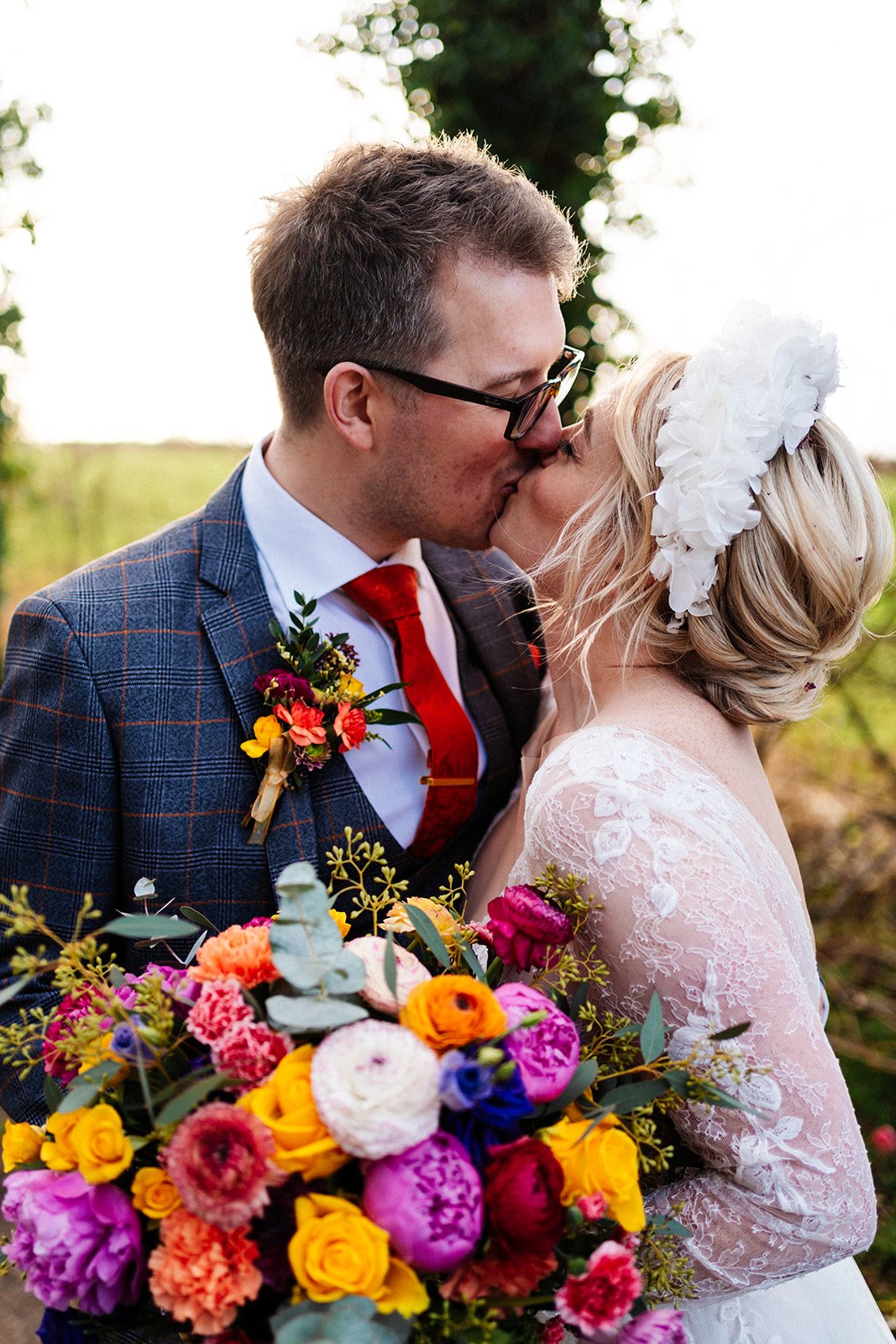 colourful portrait image of bride and groom kissing , very colourful bouquet and the bride is wearing a lace long sleeved dress. the normans York wedding